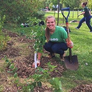 Natalie squatting next to a recently planted tree(© 2018 Erin MacDonald / LEAF)