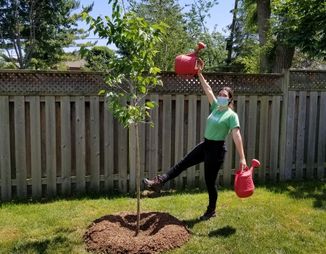 ©2021 Adriana Rezai-Stevens / LEAF Adriana with watering cans next to newly planted tree