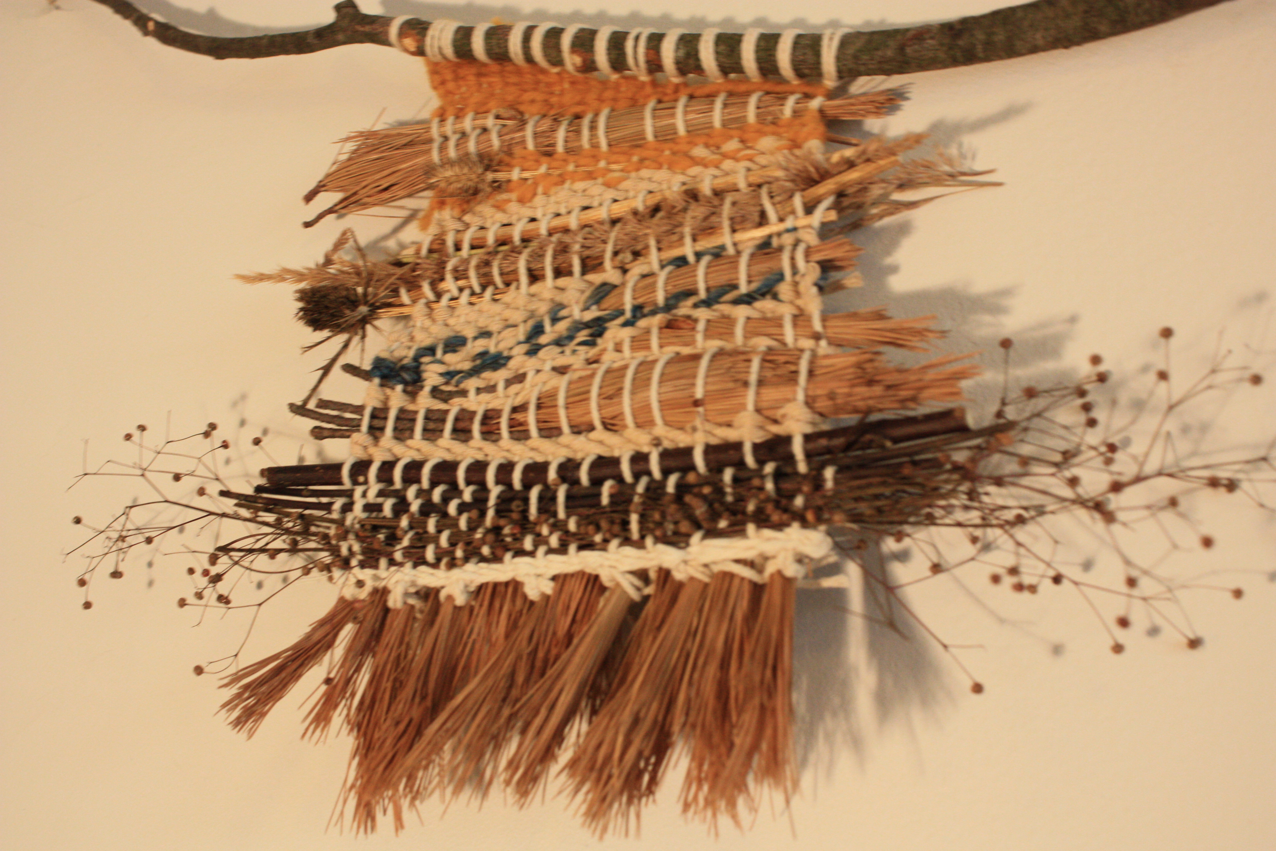 Close-up of textures — seed heads, grasses, and yarn woven together. 