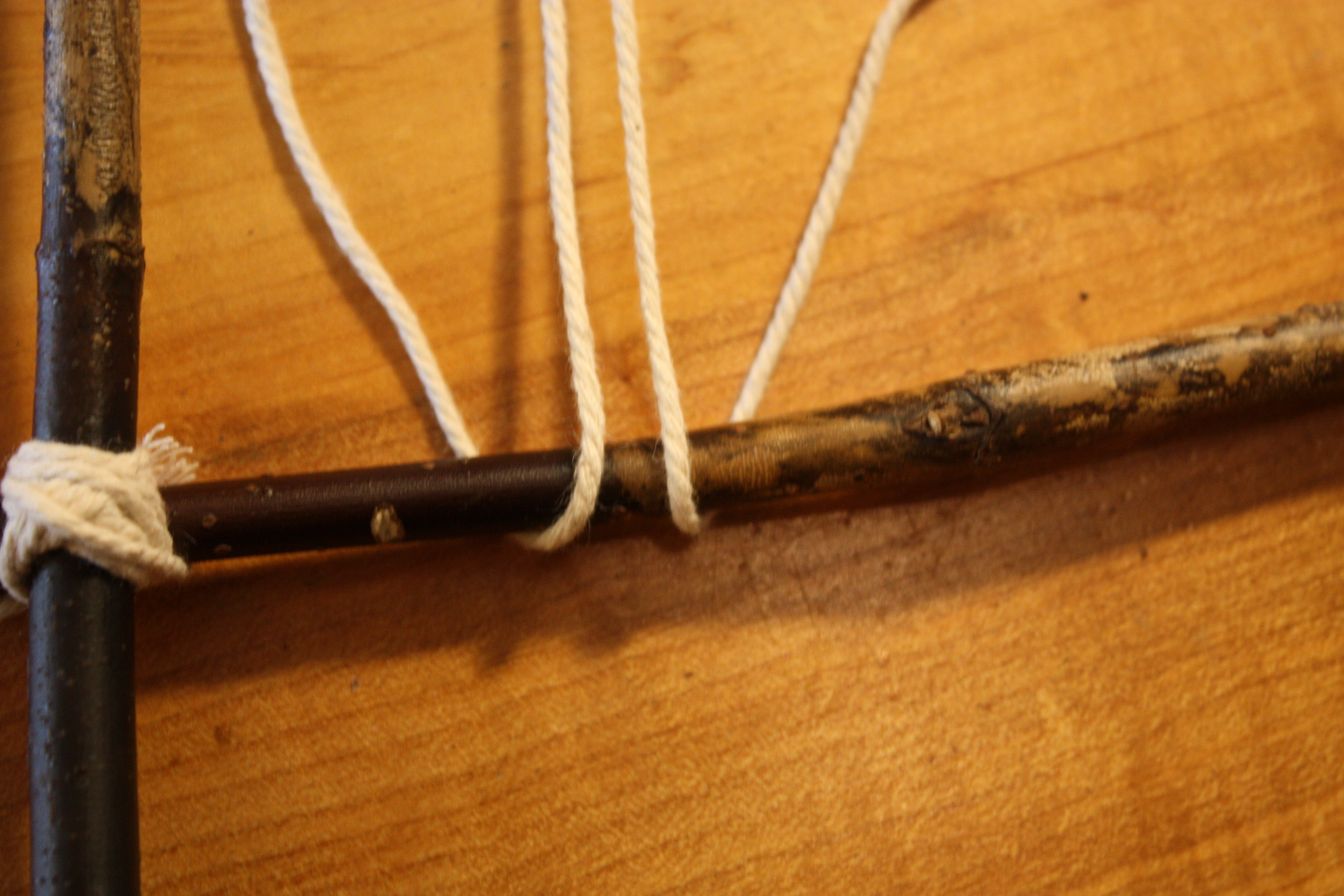 Sequence of knotting and securing the warp string to the bottom branch.