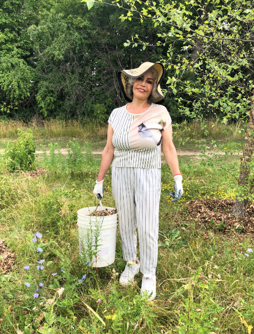volunteer posing for camera while holding a bucket of mulch at a LEAF stewardship event