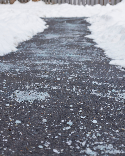 Road salt on a paved path with snowbanks to either side