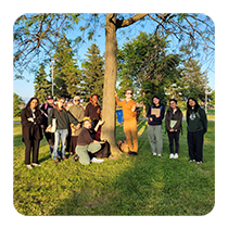 2024 Young Urban Forest Leaders posing next to tree in a park (© 2024 Jess Wilkin / LEAF)