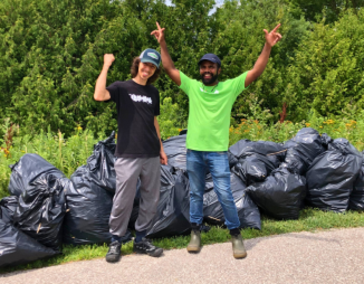 LEAF staff and volunteer posing with bags filled with invasive plant material
