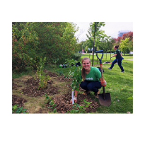 Young woman proudly showing her planted tree