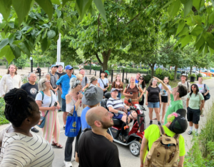 crowd of people gathered around a LEAF staff member, looking up at a tree