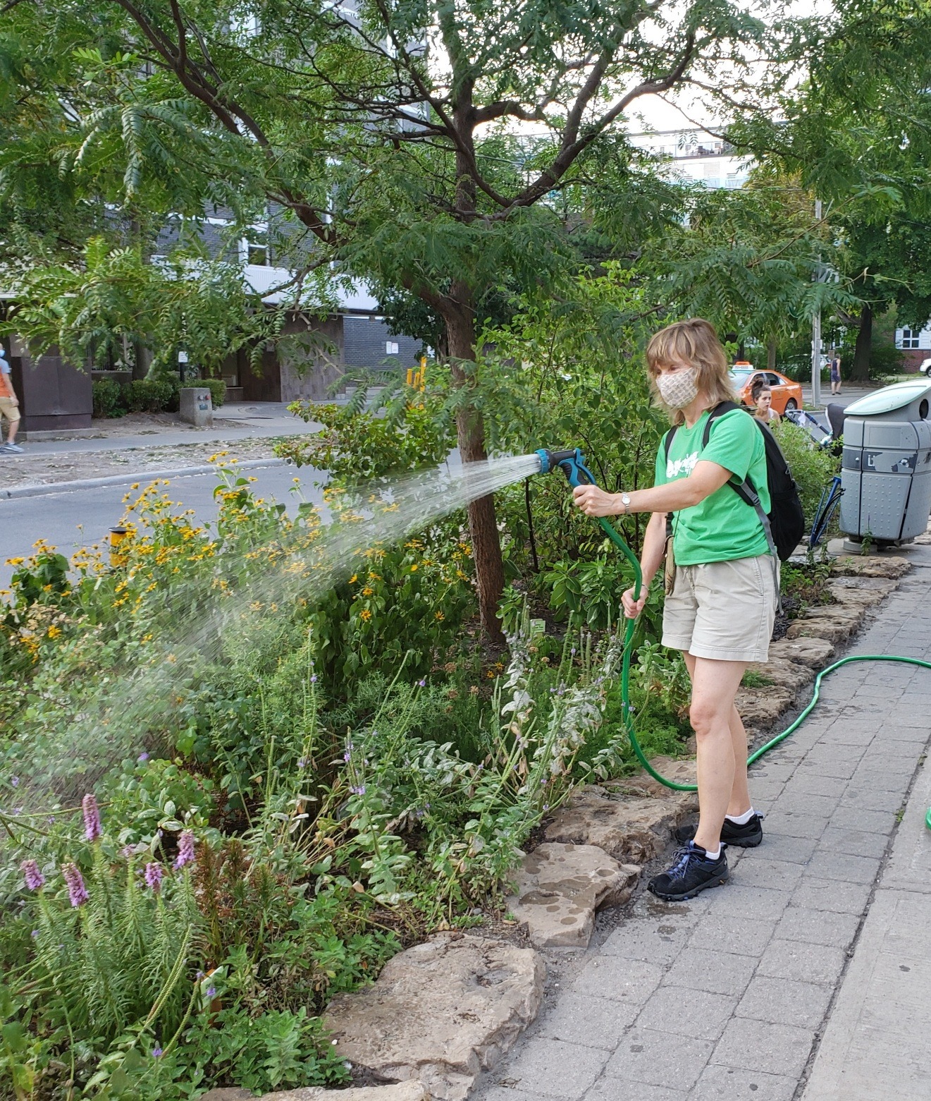 young woman watering a street-side garden(© Arleen Schenke / LEAF)