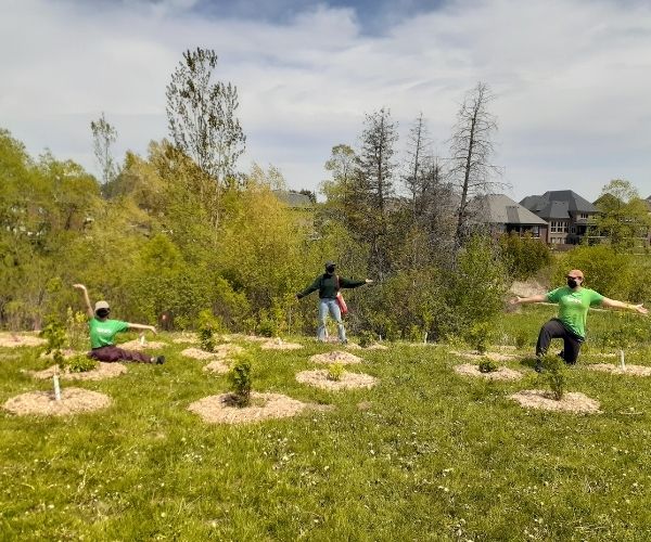 Danielle, Simran and James sitting with newly planted trees(©2021 Brian Millward / LEAF)