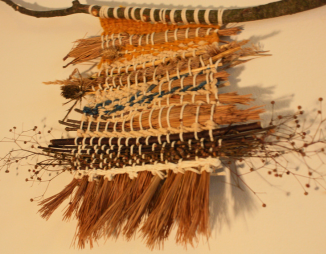 Close-up of weave wtih seed heads, grasses, and yarn woven together